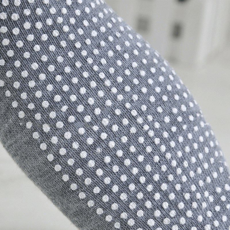 Close-up of sports anti-slip breathable women's socks with white massage granules on grey fabric, perfect for active wear.